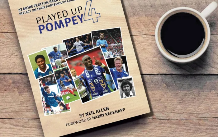 Photo of Neil Allen's Played Up Pompey 4 book on a desk next to a cup of coffee