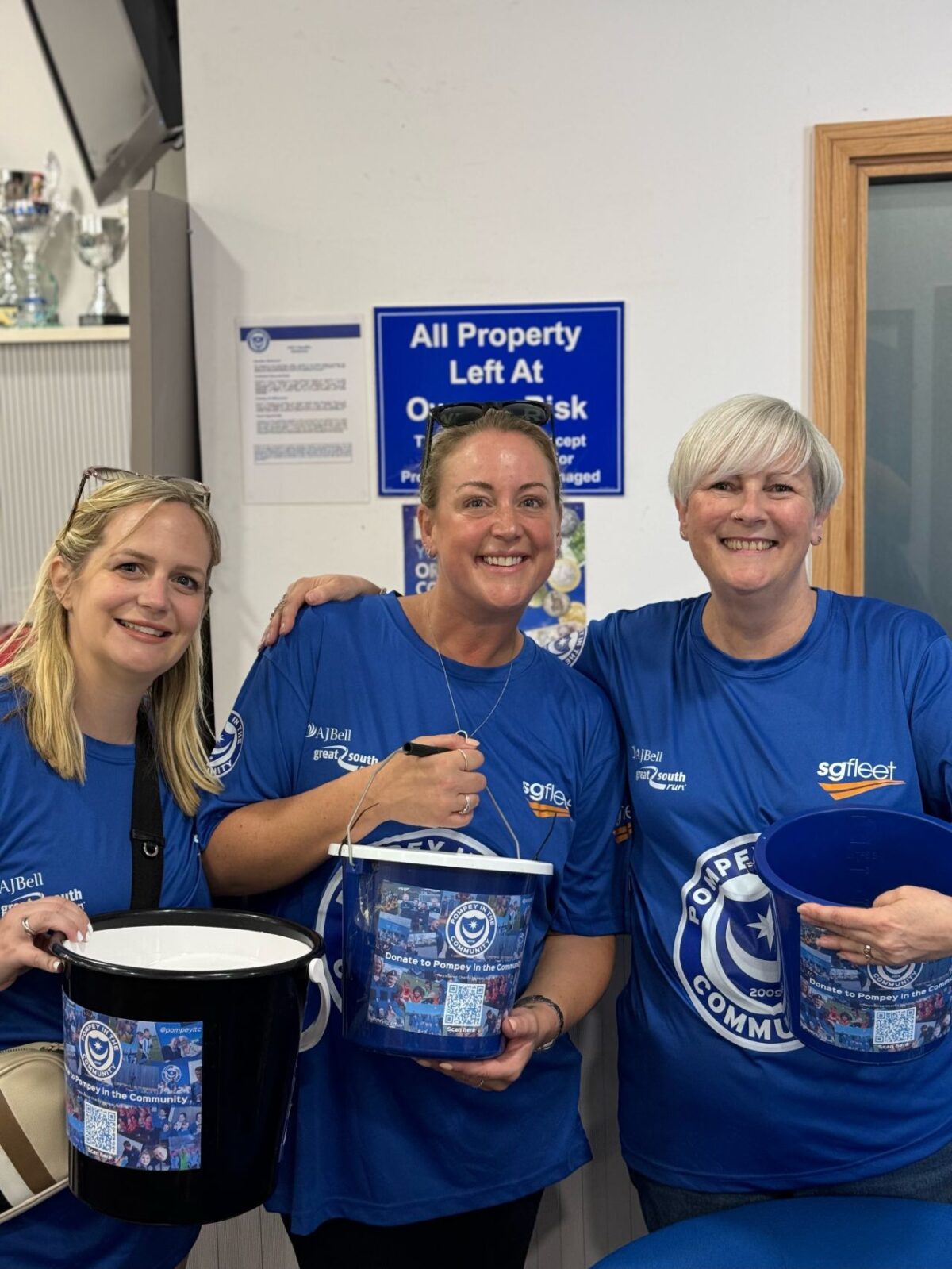 Three ladies wearing Pompey in the Community t-shirts with buckets for a collection